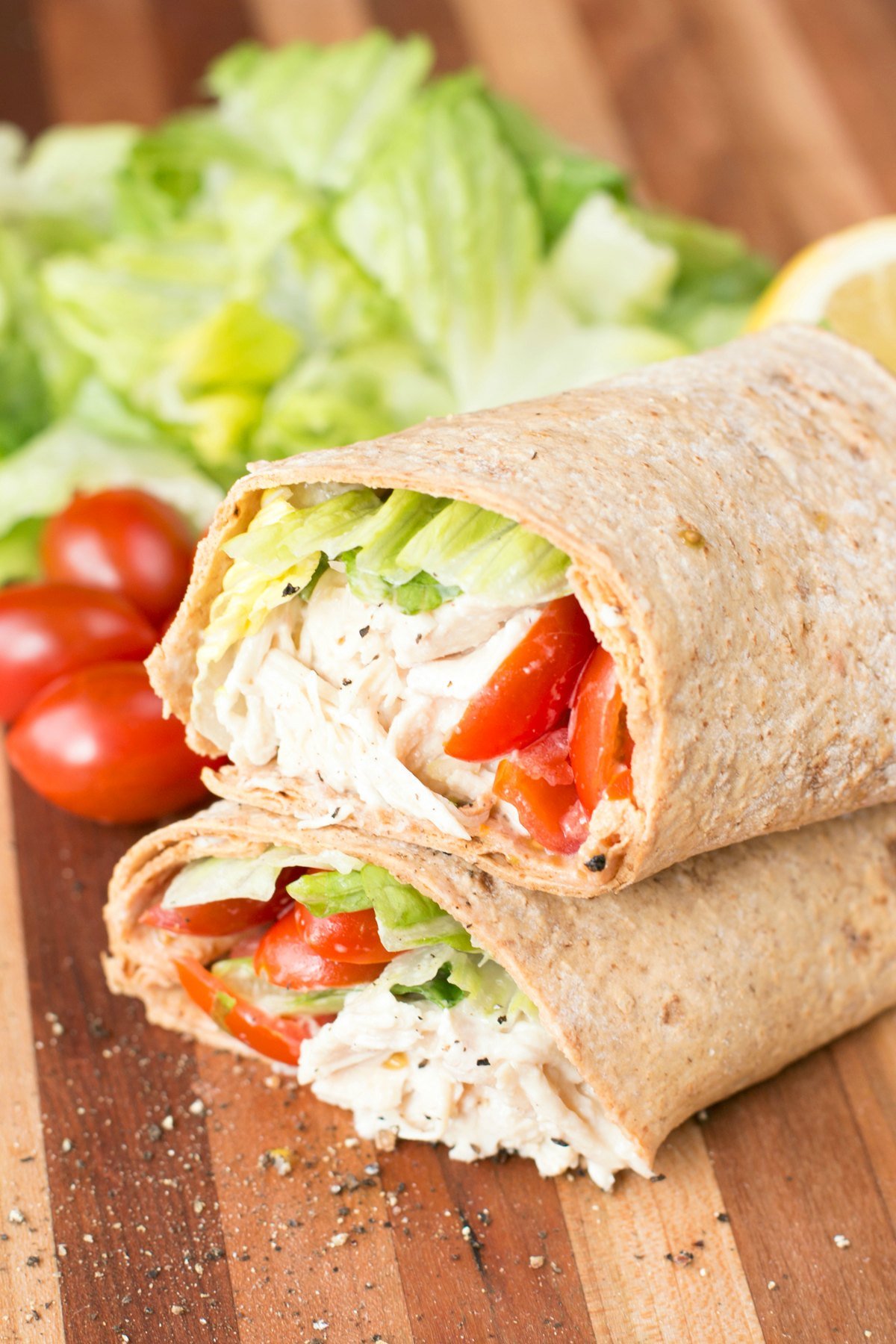 Close up picture of a chicken caesar wrap sliced in half on a cutting board