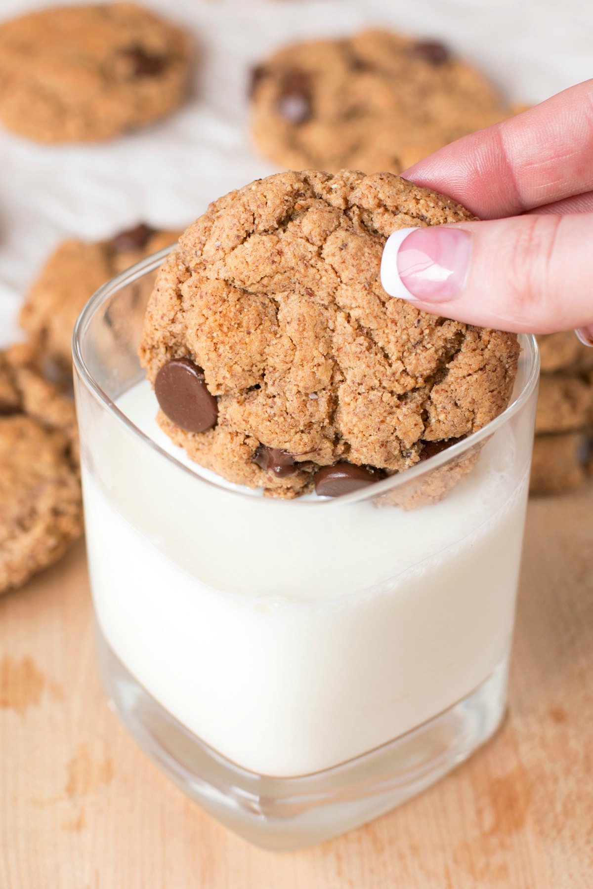 Dunking a chocolate chip almond butter cookie into a glass of milk