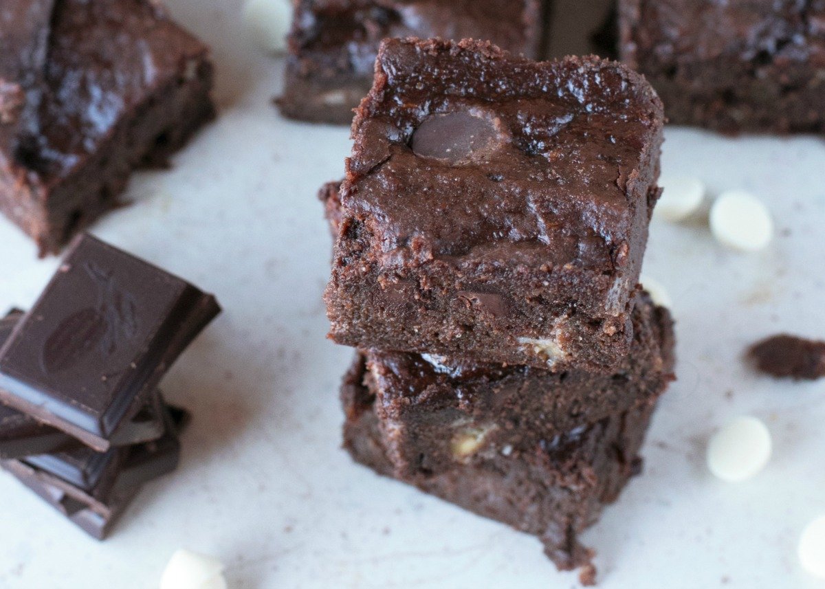 Stacks of cut triple chocolate brownies on parchment paper with chips and chunks of chocolate