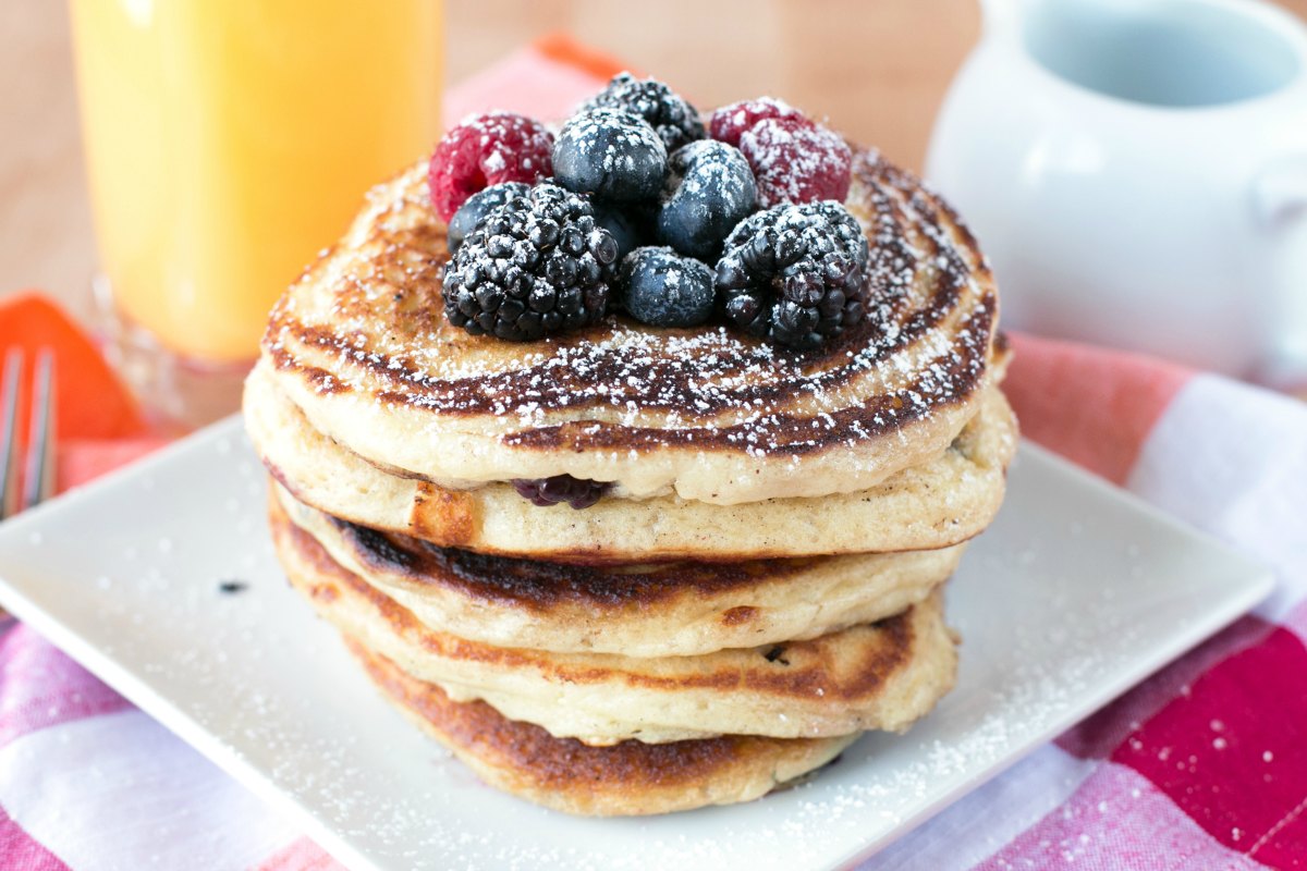 A short stack of buttermilk pancakes topped with mixed berries