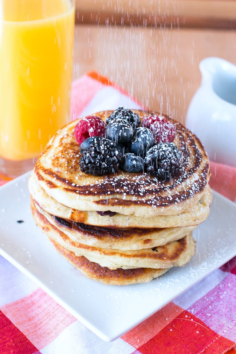 Blackberries, raspberries, and blueberries on top of a stack of pancakes