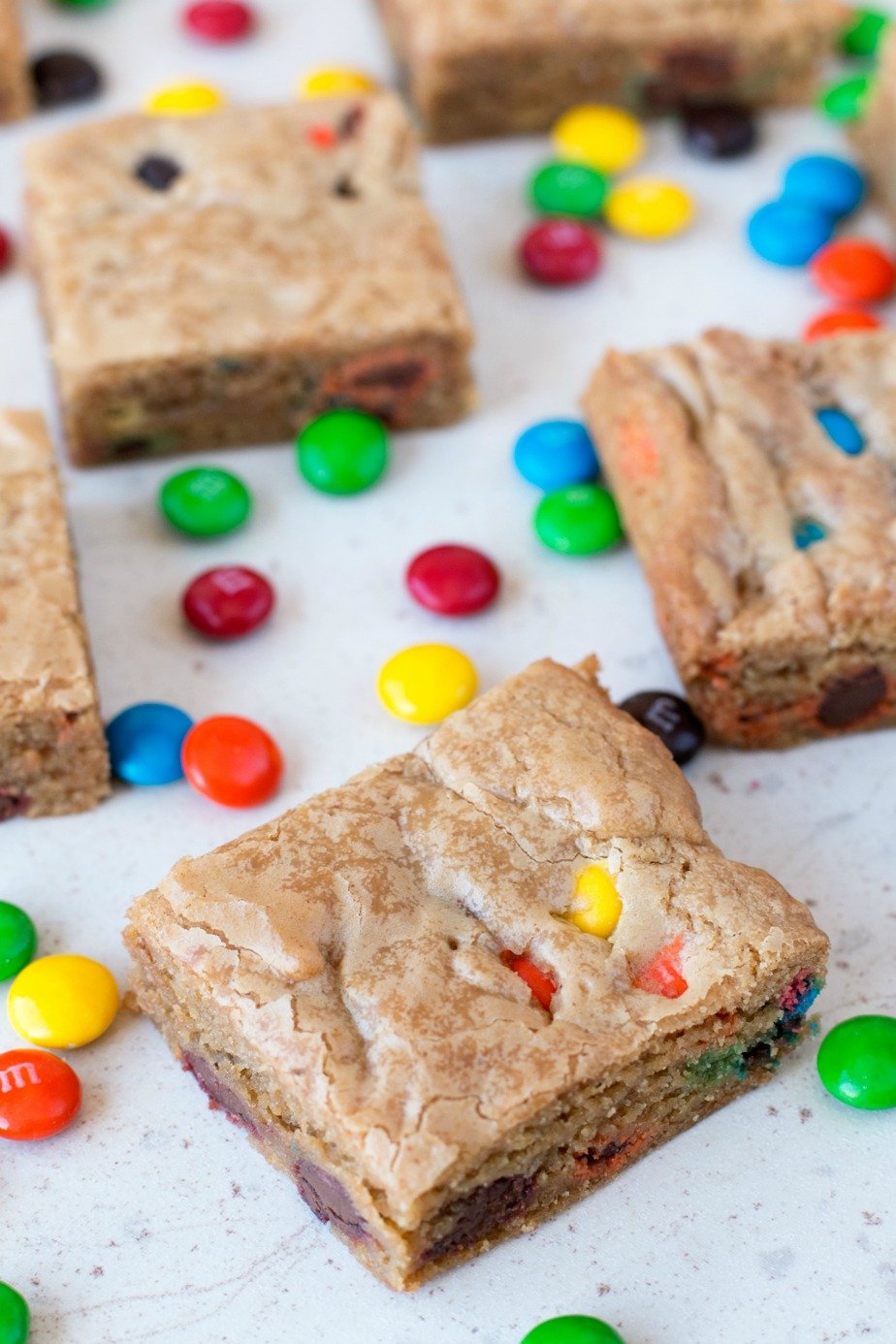 Brown Butter Blondies with M&M's cut into squares and laying on a white surface