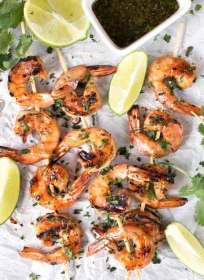 Agave Cilantro Shrimp Skewers with dipping sauce and lime on parchment paper.