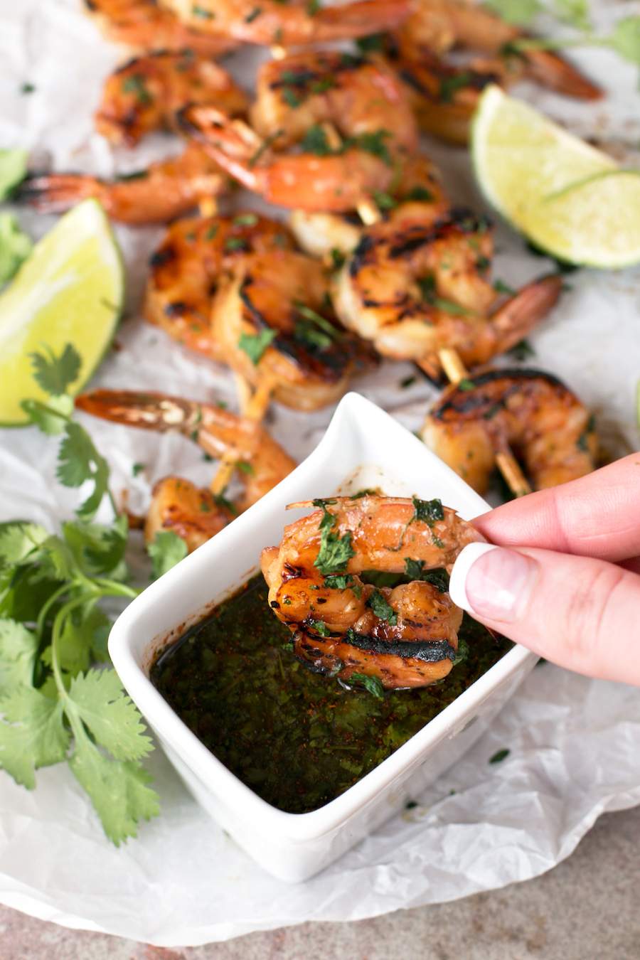 Someone dipping Agave Cilantro Shrimp Skewers into spicy dipping sauce.