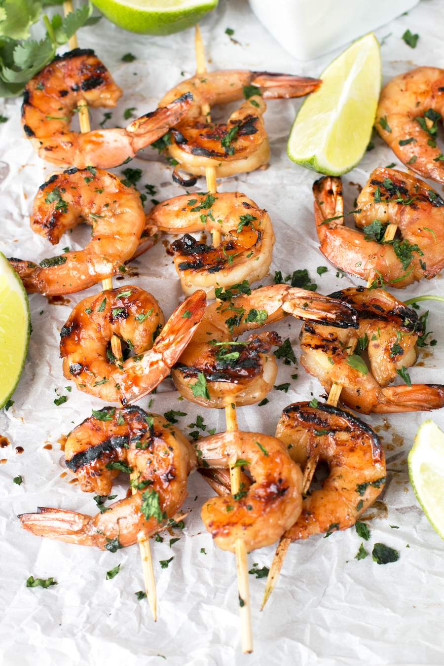 Agave Cilantro Shrimp Skewers on parchment paper with lime and cilantro