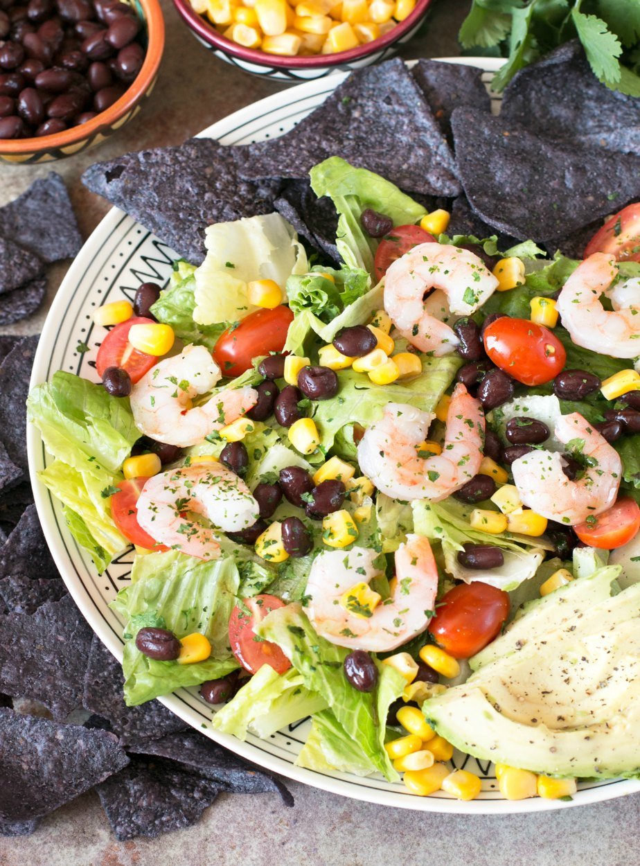 Mexican Shrimp Taco Salad on a white plate surrounded by blue corn tortilla chips