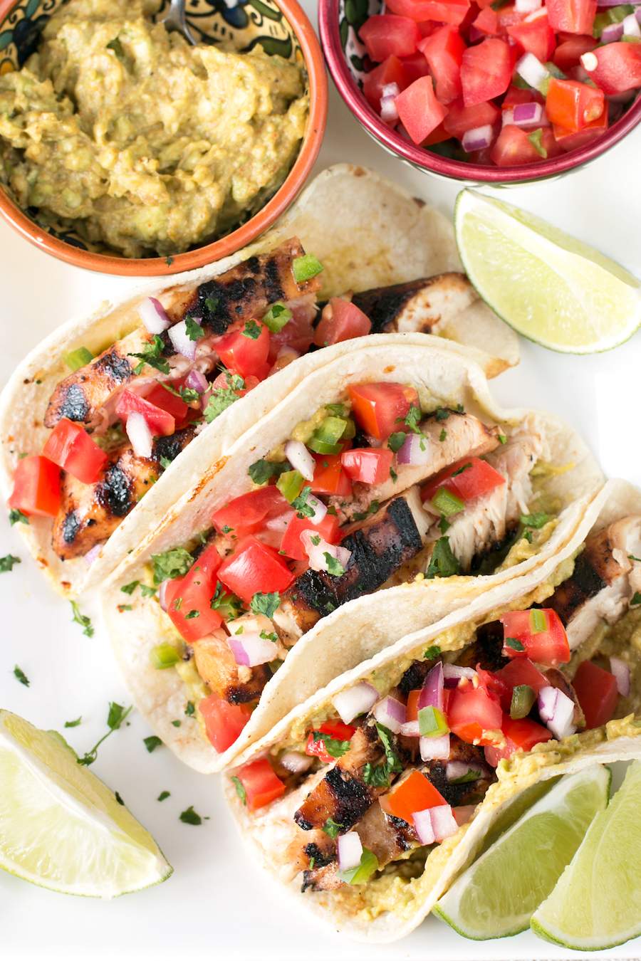 Mexican Chicken Tacos next to a bowl of guacamole and pico de gallo