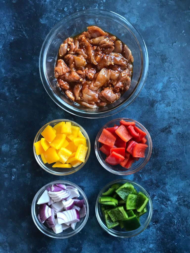 Ingredients for BBQ chicken Skewers - marinated chicken, yellow, red, and green bell pepper and red onions