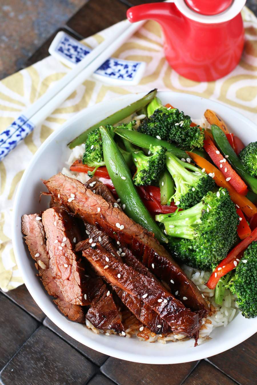 Soy Marinated Flank Steak Stir-Fry in a white bowl with white and blue chopsticks on a white and brown napkin