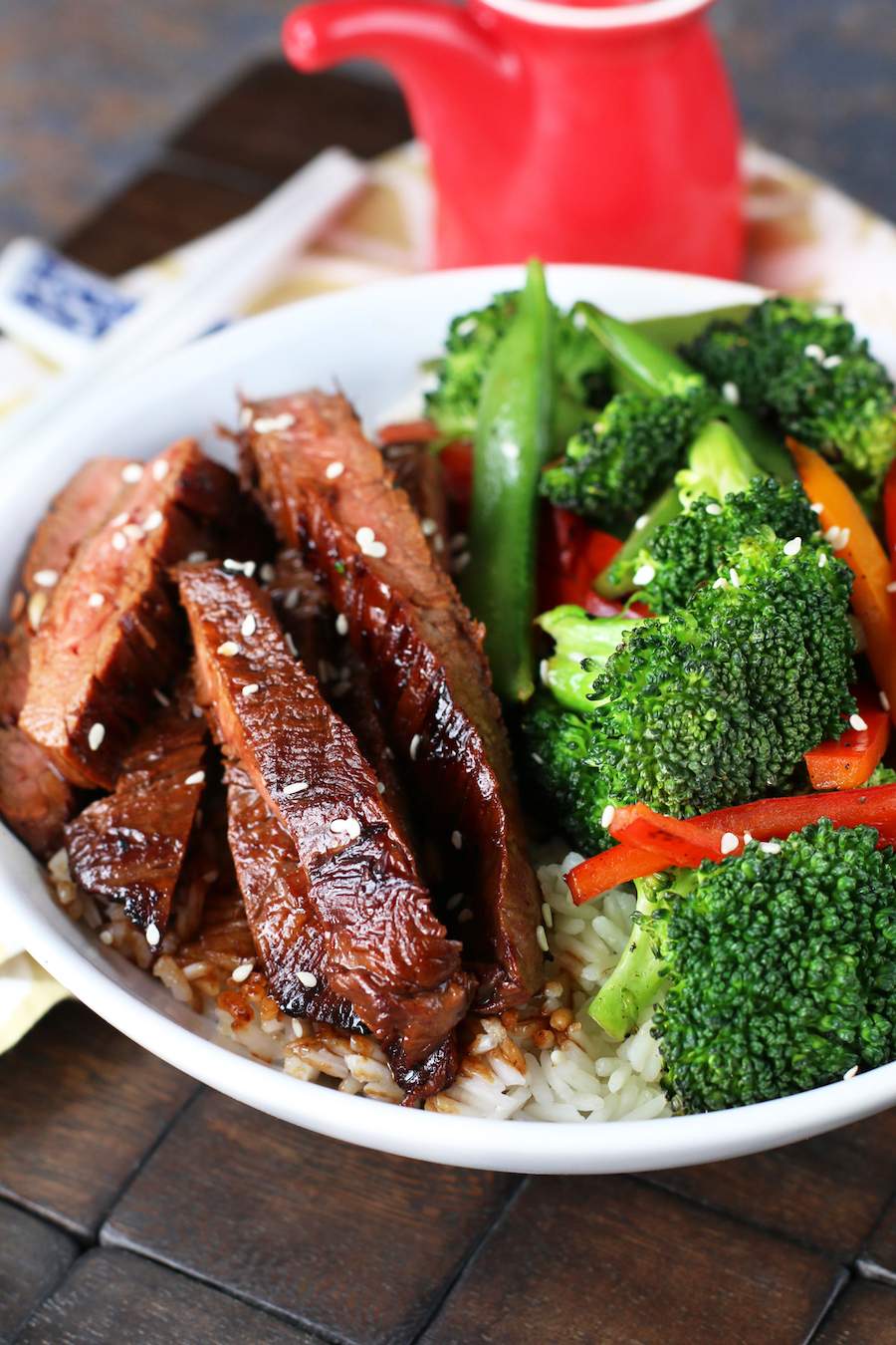 Image of Soy Marinated Steak Stir-Fry in a white bowl with broccoli and a red soy sauce container.