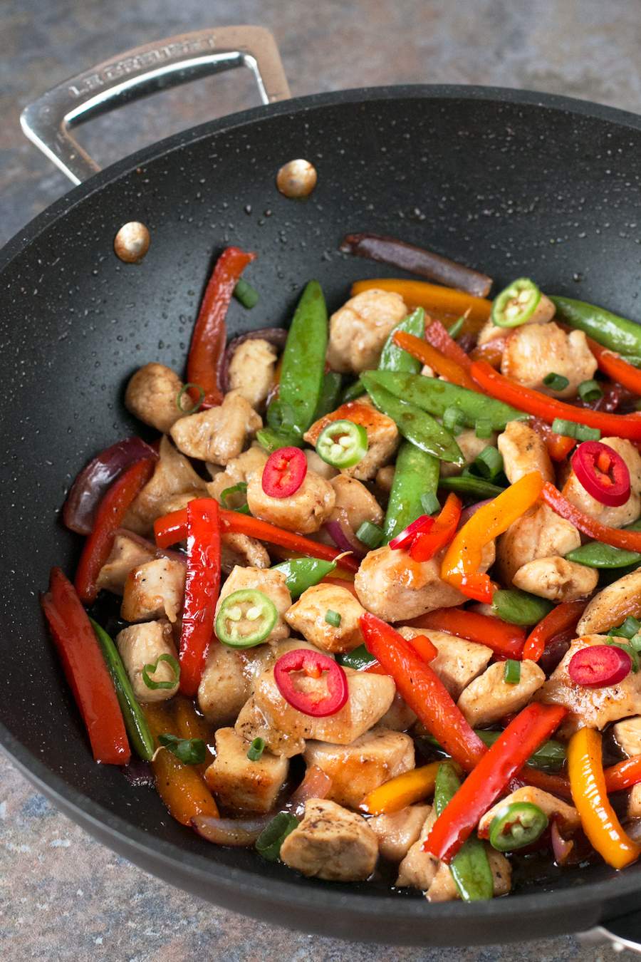 Sweet and Spicy Chicken Stir Fry in a dark non-stick skillet.