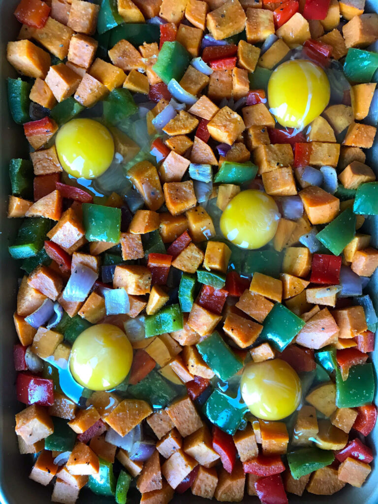 sweet potatoes, eggs, and peppers on a sheet pan