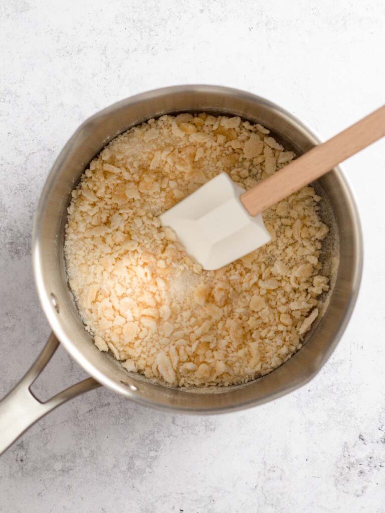 Sugar forming golden clumps in a saucepan.