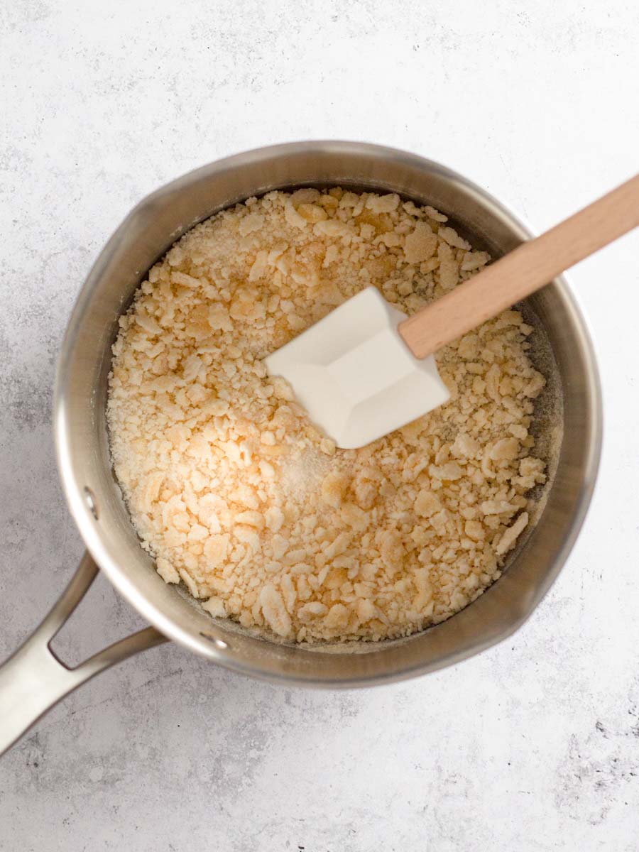 Sugar forming golden clumps in a saucepan.