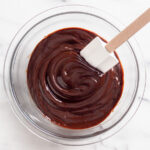 Mixing chocolate ganache in a bowl with a spatula.