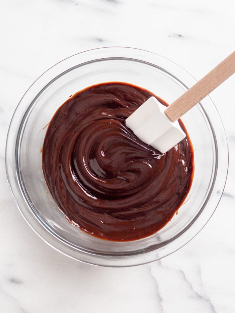 Mixing chocolate ganache in a bowl with a spatula.