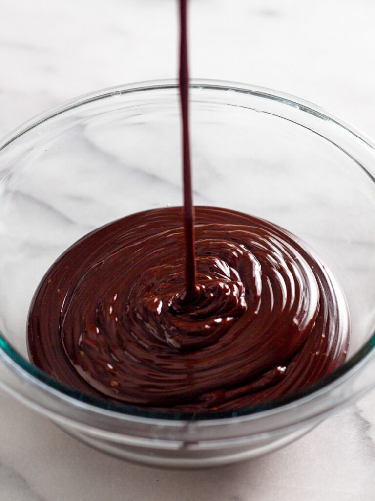 Chocolate ganache being drizzled into a bowl.