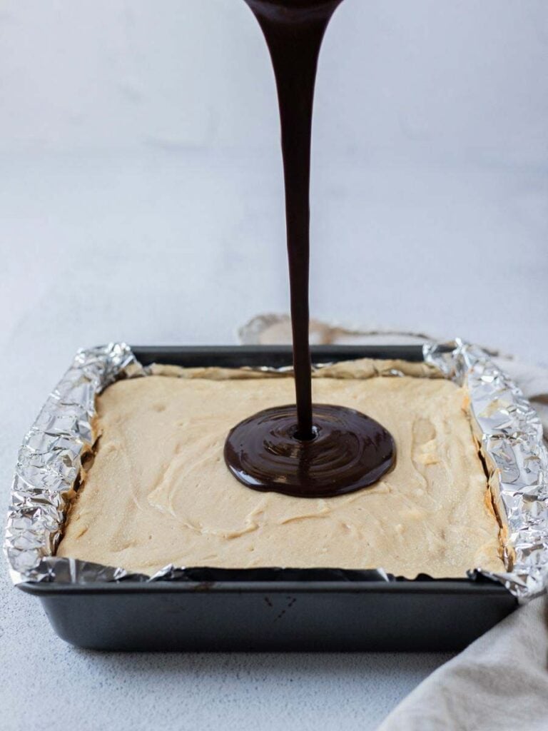 a shot of the chocolate ganache being poured onto the cheesecake