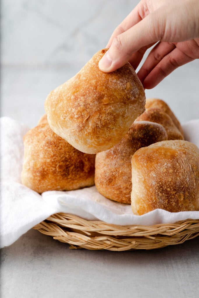 Hand lifting up a ciabatta bread roll.