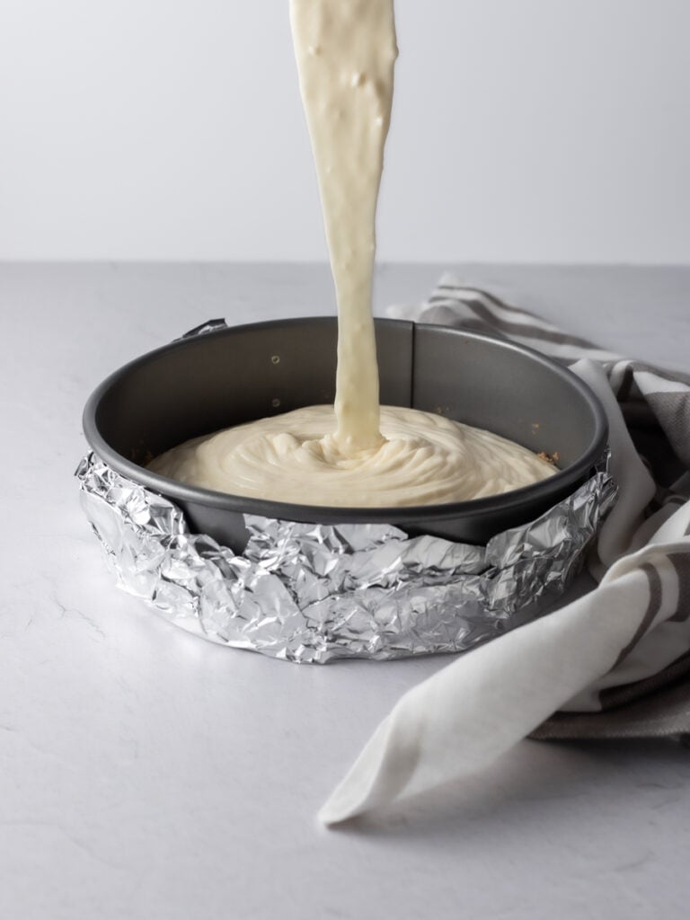 Cream cheese batter being poured into a prepared pan.