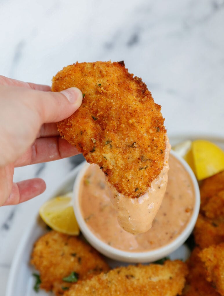 chicken strip being dipped into the sauce