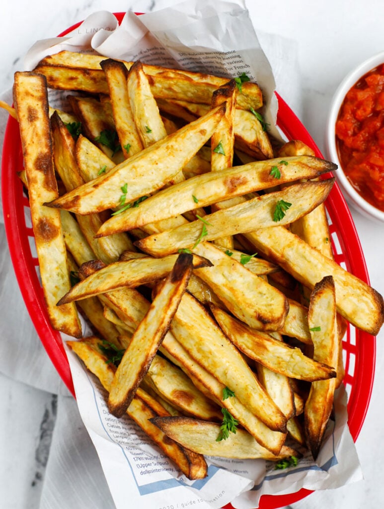 Top down shot of sweet potato fries in a red basket.