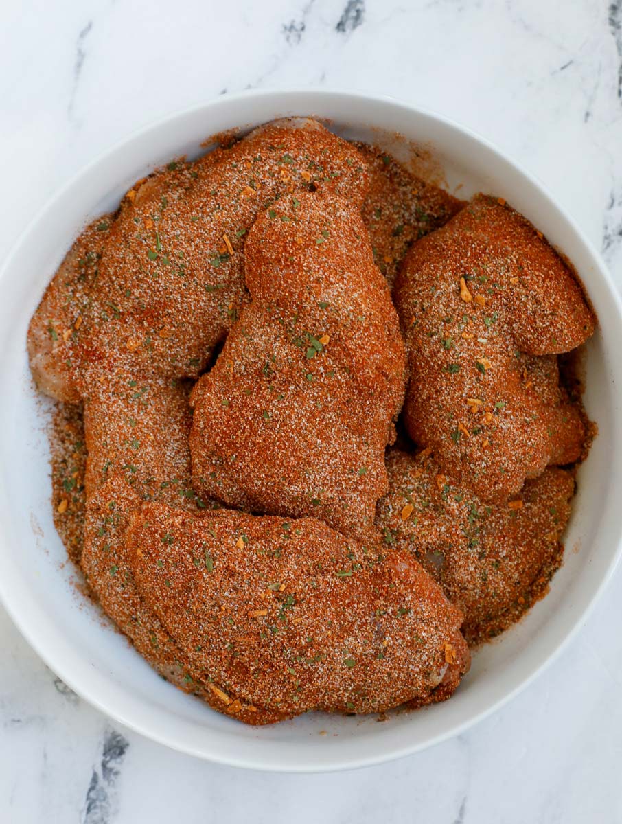 Raw chicken thighs in a bowl.