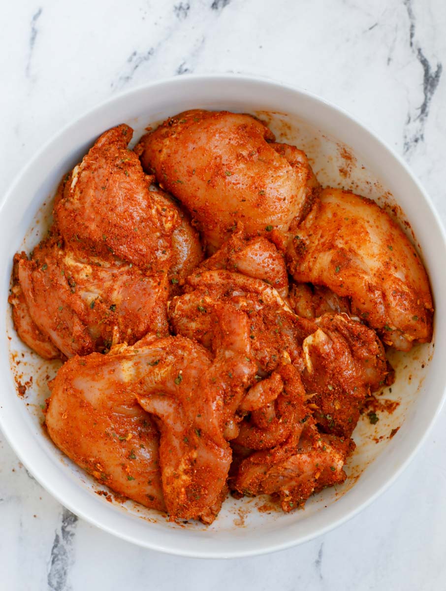 Chicken thighs marinating in a bowl.