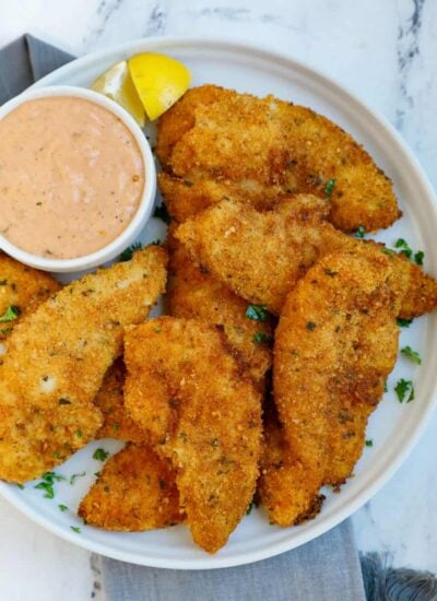 Chicken strips on a plate with sauce.