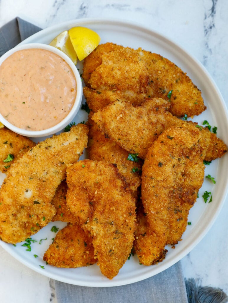 Chicken strips on a plate with sauce.