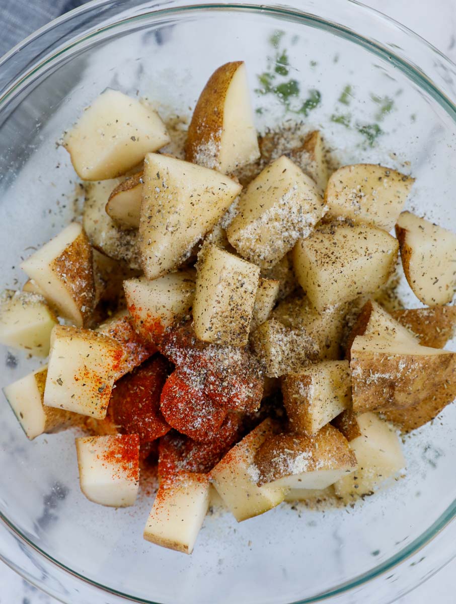 Seasoning cut up potatoes before air frying.