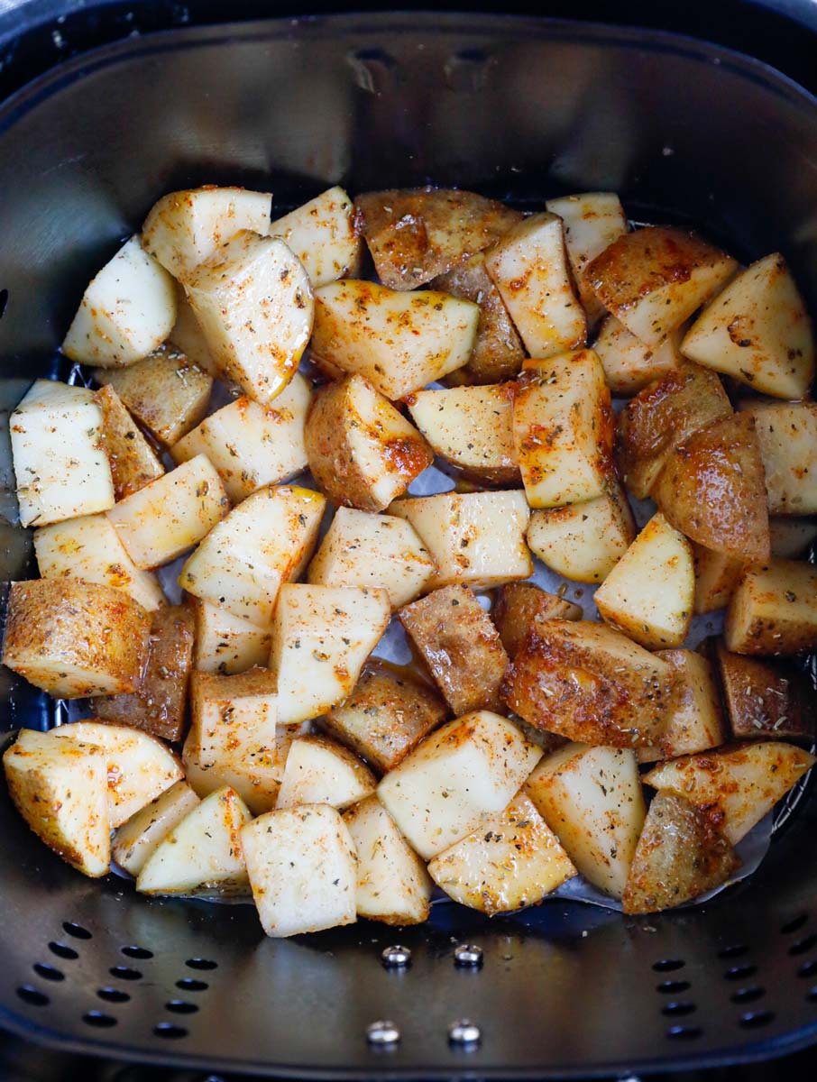 Potatoes in an air fryer basket before cooking.