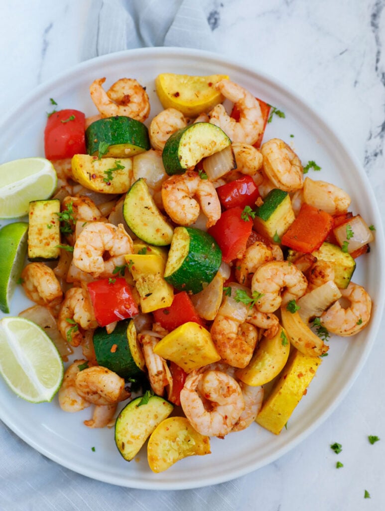 Top down shot of air fryer shrimp and vegetables on a white plate.