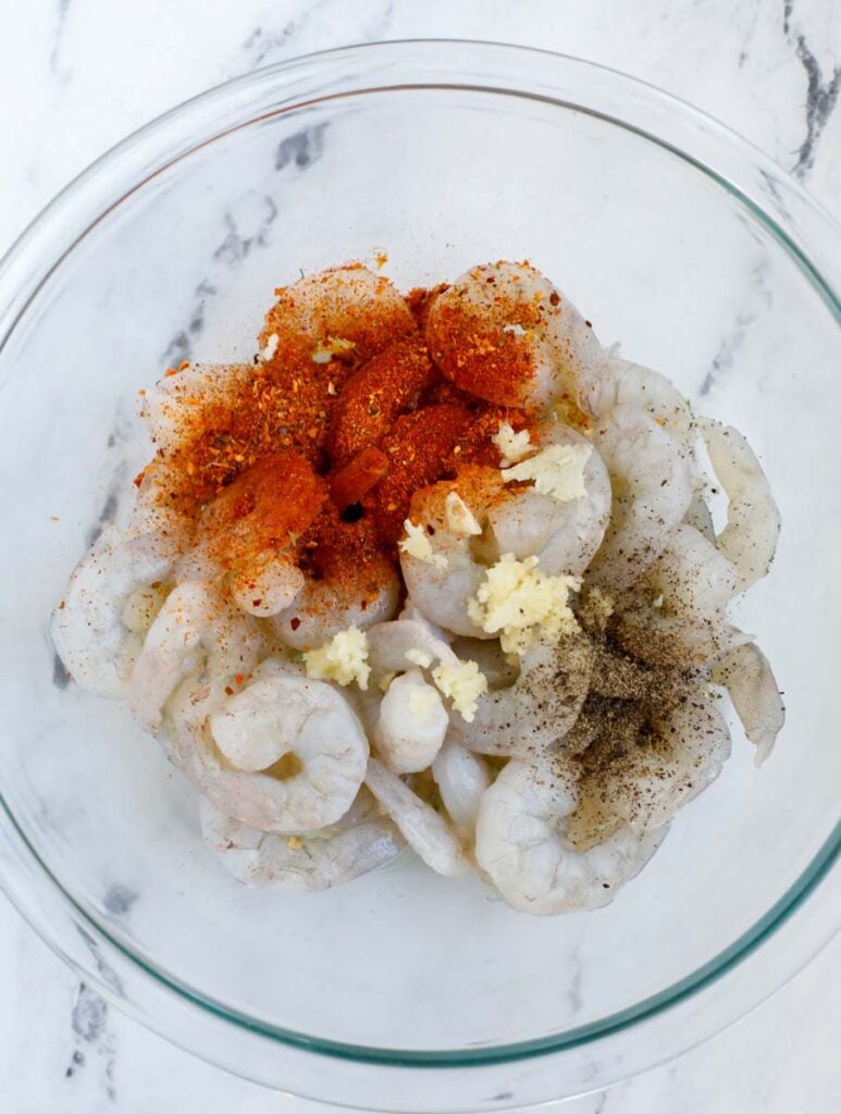 Raw shrimp and seasoning in a bowl.