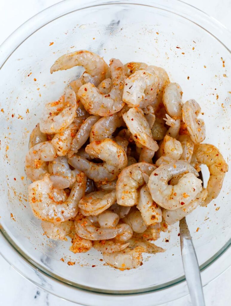 Shrimp being coated in seasoning.