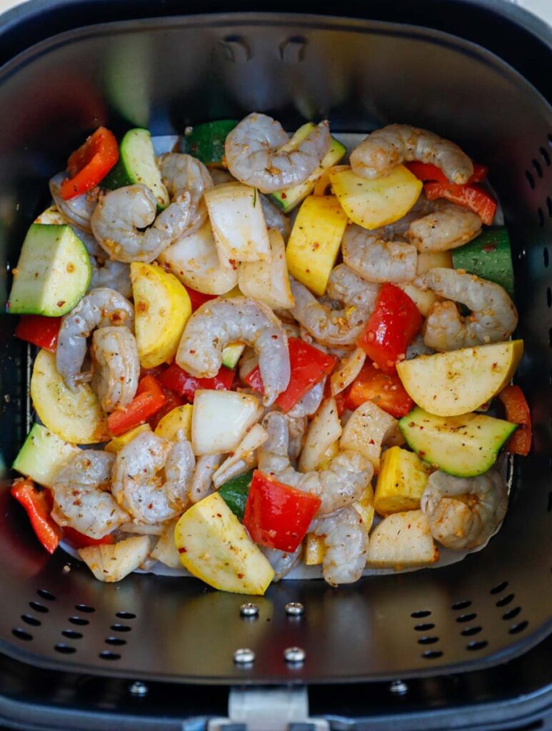 Raw shrimp and vegetables in an air fryer.