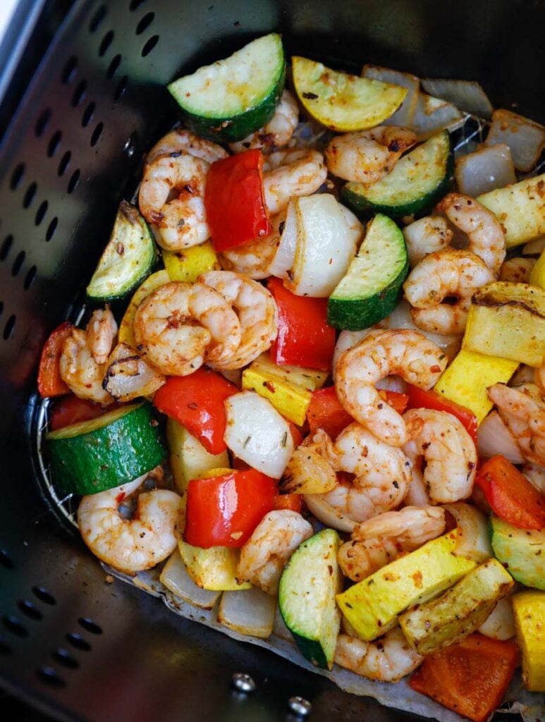 Cooked shrimp and vegetables in an air fryer.