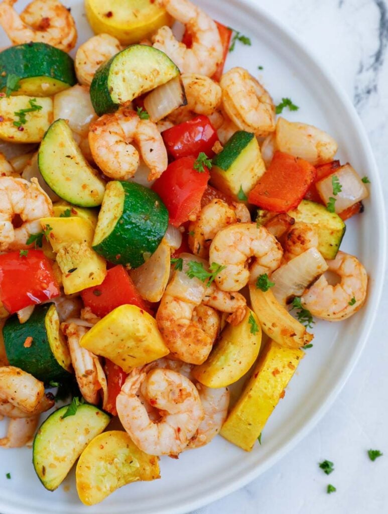 Top down shot of air fryer shrimp and vegetables on a plate.