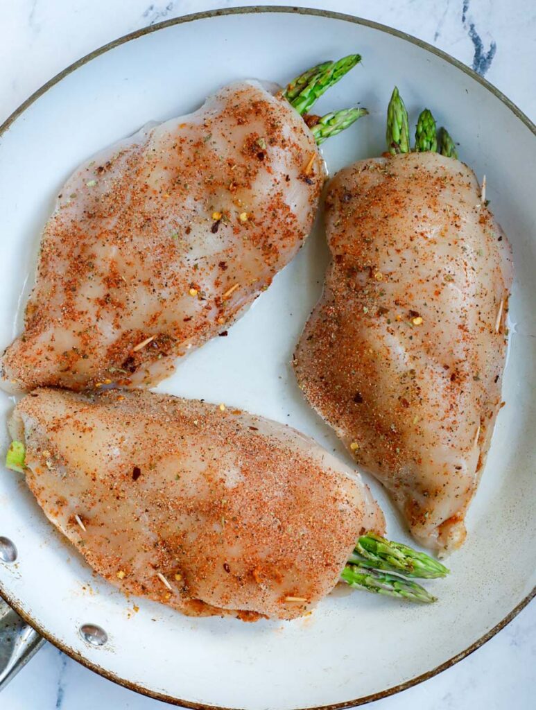 Three stuffed chicken breast in a skillet.