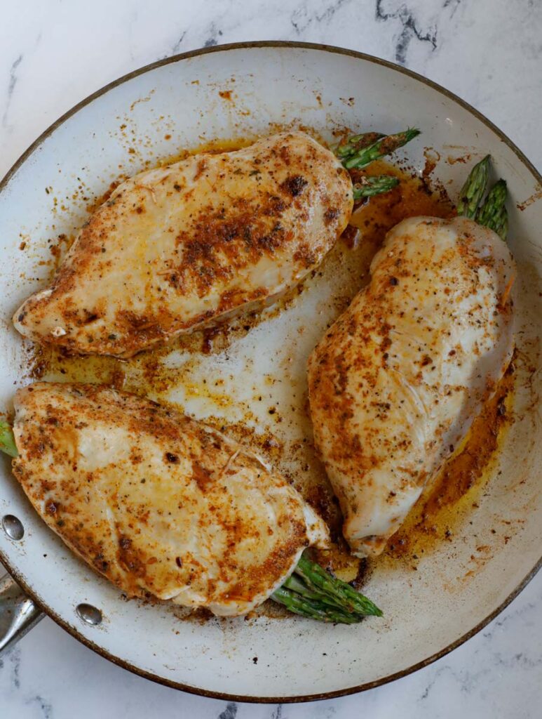 Three stuffed chicken breast in a skillet.