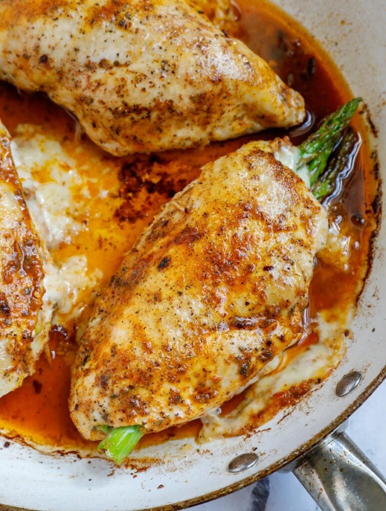 Top down shot of asparagus stuffed chicken in a skillet.