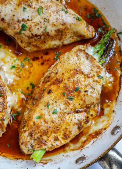 Top down shot of asparagus stuffed chicken breasts in a skillet.