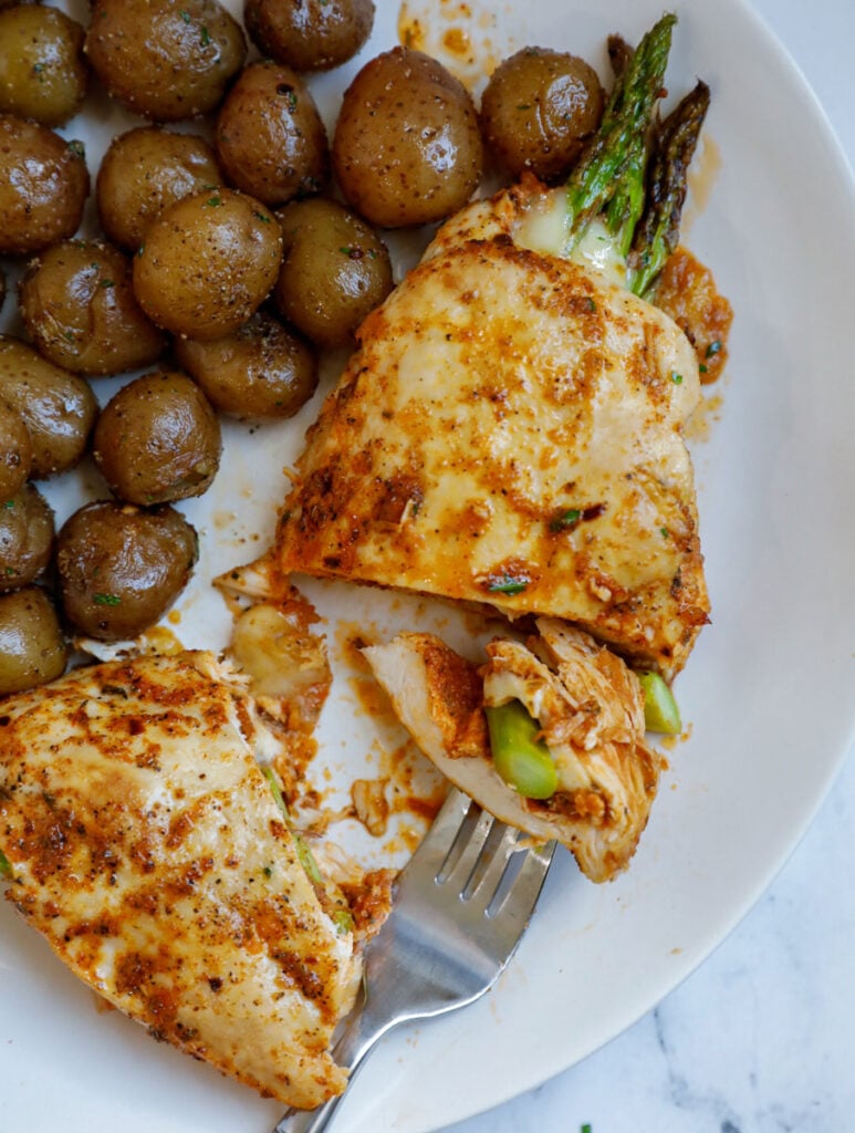 Top down shot of asparagus stuffed chicken with potatoes on the side. 