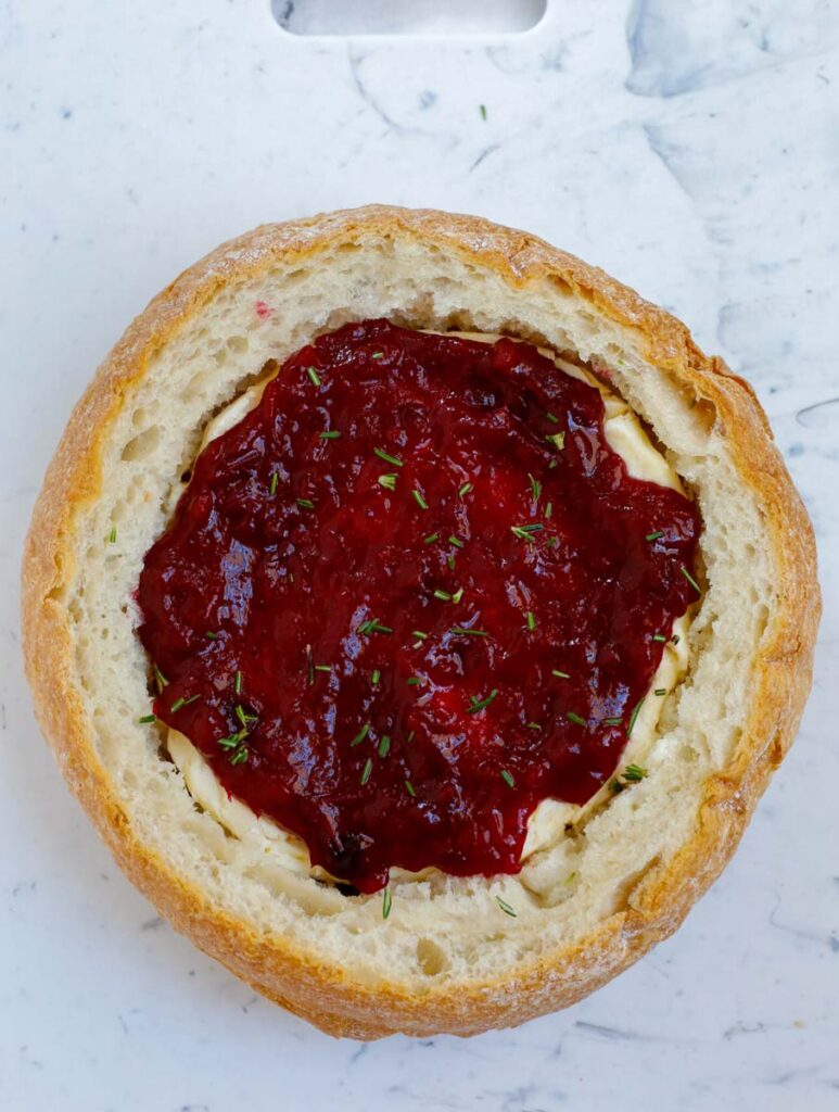 Cranberry sauce on top of brie in bread bowl.