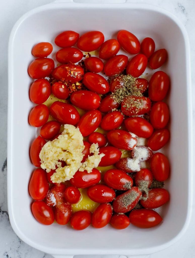 Tomatoes in a baking dish with seasoning.