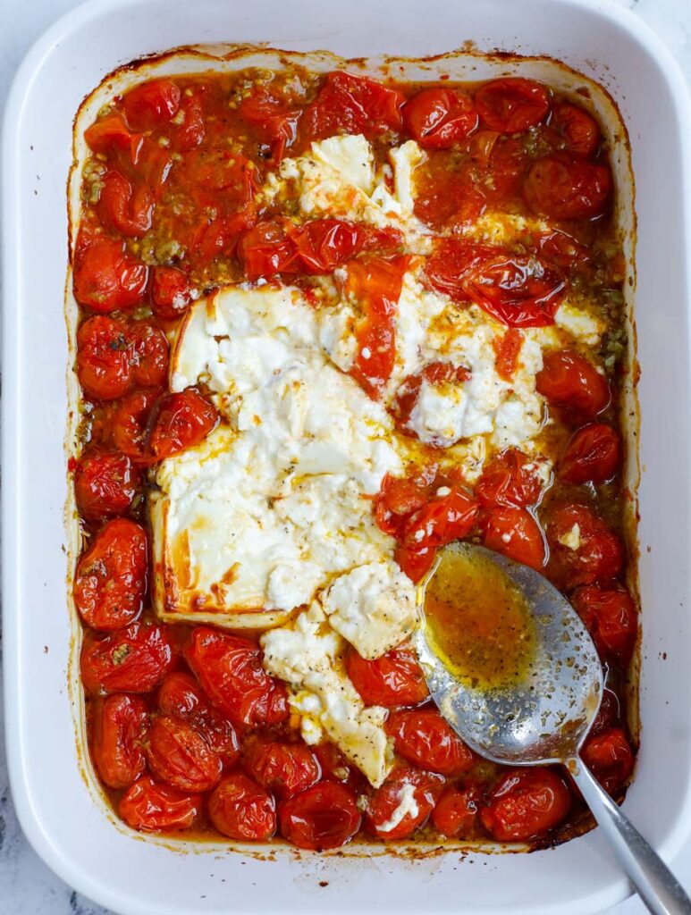 Crushing the melted feta in a baking dish.