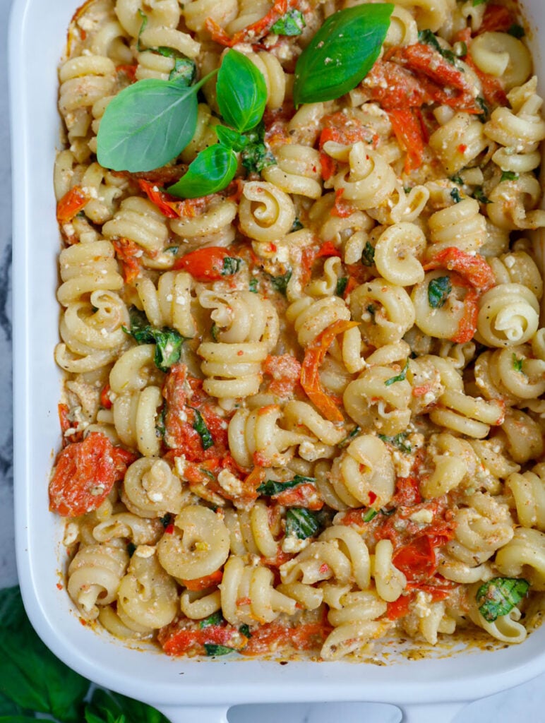 Baked cheese pasta in a casserole dish with basil garnish.