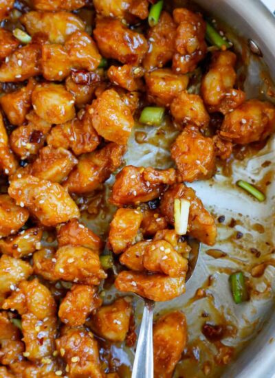 Close up of a spoonful of crispy general tso chicken.