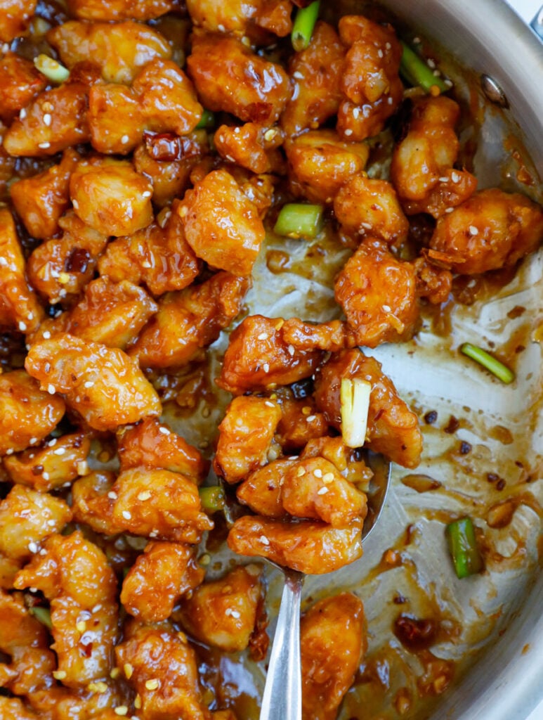 Close up of a spoonful of crispy general tso chicken.