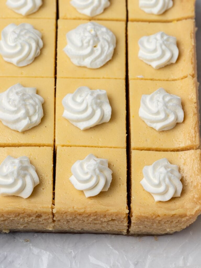 lemon bars cut out and topped with whipping cream